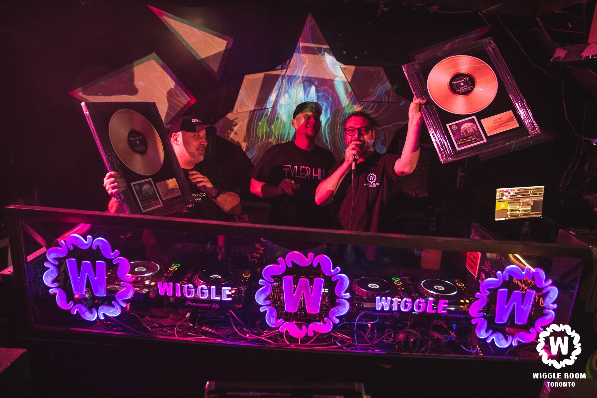 Three DJs, one with a record held up