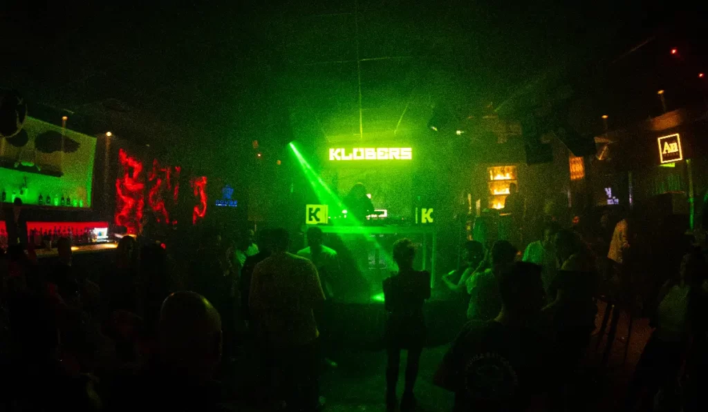 Nightclub dance floor with green laser and DJ
