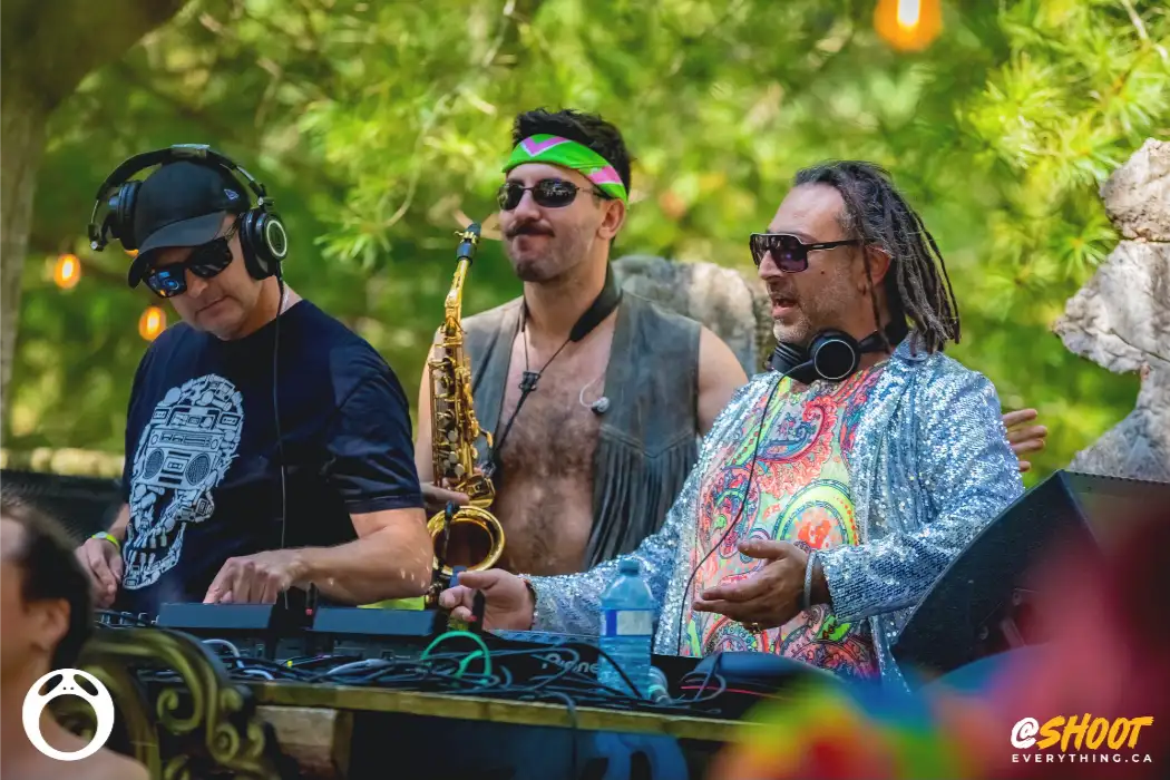 Djs and sax player outside in sunshine